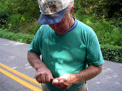 A gentleman carving a face into a buckeye